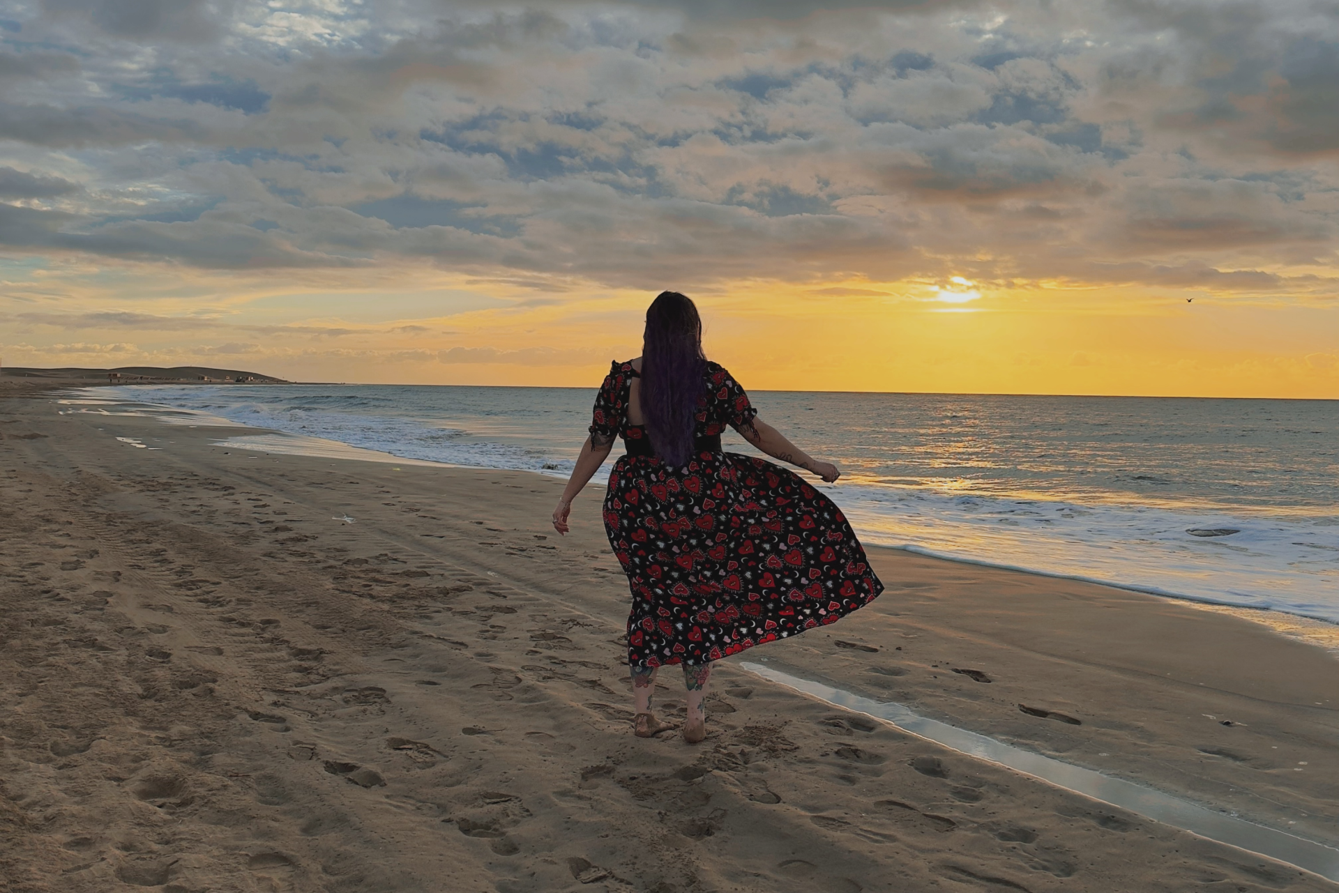Luisa is looking out to sea with a gorgeous yellow sunrise in front of her, experiencing solo travel for the first time